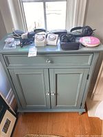 Front view of the green wooden cabinet with contents on top.