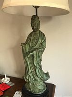 Frontal view of the patinated metal deity figure lamp showing full figure and base