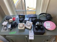 Full view of all items on table showing electronic accessories, clocks, binoculars, and tripods