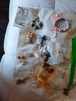 Overview of lot jewelry items displayed on fabric including earrings, bracelets, brooches mostly in plastic bags