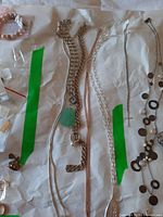 Full spread of necklaces and watches on white background with green tape