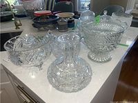 Overview of assorted crystal pieces including bowls, vase, and covered dishes displayed on kitchen counter.