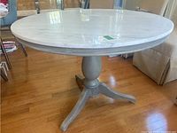 Overall view of oval marble tabletop and painted wood pedestal base