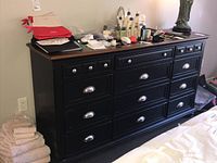 Front view of entire dresser showing wood top, black painted body, hardware and drawer layout