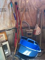 Electrolux vacuum, cleaning tools including mops, brooms, dusters, and blue mop bucket with wringer in basement setting