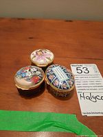 Top view of three Halcyon Days small enamel and metal jewelry boxes with floral designs.