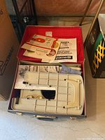 Open case showing Husqvarna 2000 sewing machine and manuals inside the hard plastic case.