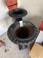Two black cast iron urn planters side by side, showing full front view