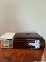 Wooden jewelry box and plastic organizer side by side on wooden surface