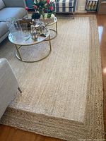 View of full jute area rug placed in living room under coffee tables and seating