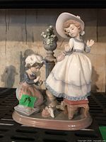 Front view of entire figurine group showing both girls and pedestal