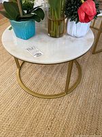 Photo of round marble top table with brass base showing top surface and floral decorations.