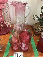 Set of one cranberry etched crystal pitcher and five glasses with white Mary Gregory style etched children and pastoral scenes.