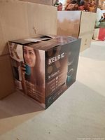 Keurig K-Select coffee maker box with side image of a woman holding a blue mug, showing product name and features.
