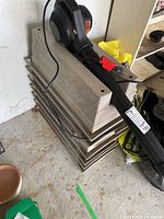 Seven beige rectangular planter boxes stacked with holes for railing mounts visible, and a black Shop Vac blower tool resting on top.