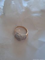 Image of women's ring featuring cluster of stones and gold tone band on a white background.