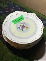 Stack of plates and saucers with a note indicating 13 saucers, showing floral pattern with gold trim on porcelain.