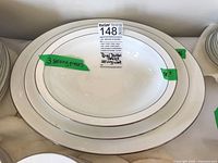 Three white Royal Doulton serving pieces stacked with green tape, including two oval plates and one bowl with silver rims.