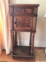 Front view of vintage oak smoker's cabinet showing drawer, cupboard door, turned legs, and bottom shelf