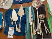 Overview of most items arranged on blue cloths showcasing the variety of serving utensils including carving set and nutcracker.
