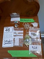 Photo showing multiple items including silver rings, earrings with blue stones, and a large pendant necklace tagged 925 sterling silver.
