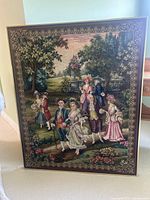 Full front view of the large framed tapestry showing detailed scene of 18th century people in a garden.
