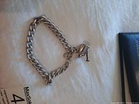Bracelet laid flat on white surface showing link chain and charm