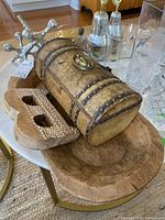 Photo showing wood treasure chest, carved letter B, and large wooden dish arranged together with glass items in the background.