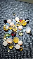 Photo of a variety of mixed natural gemstones on black textured surface showing multiple colors and cuts