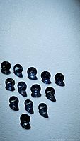 Photo showing 15 round-cut natural blue sapphires placed on flat surface, deep blue color and high clarity