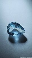 Pear-shaped sky blue aquamarine gemstone photographed on white background showing color and clarity.