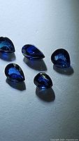 Five natural deep royal blue pear-shaped sapphires with well-cut facets showing rich royal blue color.