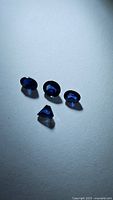 Four natural royal blue sapphires on a white background showing oval and triangular shapes