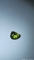 Top view of the pear-shaped apple green peridot gemstone showing its facets and color.
