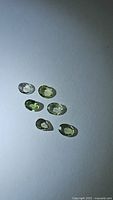 Six natural mint green sapphires displayed on white background under flash lighting showing oval shape and clarity.