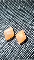 Close-up image of two peach moonstones placed side by side on a dark textured background, showing their shape, color, and facets.