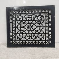 Full front view of rectangular cast iron vent grate showing black painted ornate scroll and geometric openwork pattern with a solid flat border.