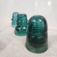 Three turquoise Hemingray glass insulators in a row, showing their shape and color detail.