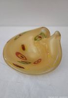 Overview photo of yellow Murano glass ashtray with floral millefiori decoration and glossy finish.