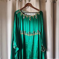 Front view of the green satin kaftan dress with gold bead and gem embroidery at neckline, waist, and cuffs.