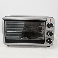 Front view of Black & Decker toaster oven showing glass door, stainless steel finish, and control knobs on right side.