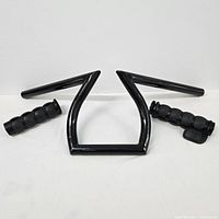 Overview photo showing the black angular motorcycle handlebar along with two black segmented rubber hand grips.