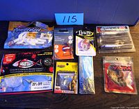Lot of 8 fishing bait and hook items from various brands including Berkley, Smartbaits, Southbend, Lindy, Yum, and Stopper Lures, shown together on table with lot number 115