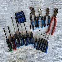 Wide view of all tools including screwdrivers, pliers, and drill bits on white cloth