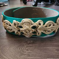 Front view of the vintage green and gold Moroccan Kaftan belt showing the gold braided embellishment with embedded green and iridescent gems.