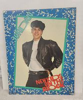 Front view of official New Kids On The Block Jordan Knight poster board with blue patterned border and photo of Jordan in black studded leather jacket, white shirt, red NKOTB logo.