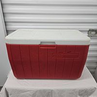Front view of the red Coleman cooler with white lid, showing exterior condition and branding.