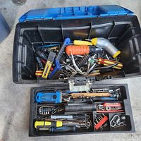 Open view of toolbox showing various hand tools including screwdrivers, wrenches, sockets, a hacksaw, and pliers