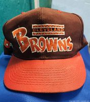 Front view of the cap showing the embroidered Cleveland Browns logo in orange and white on brown fabric with an orange visor.