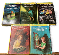 Photo showing all five vintage Nancy Drew books with varied illustrated covers and yellow spines with numbering.